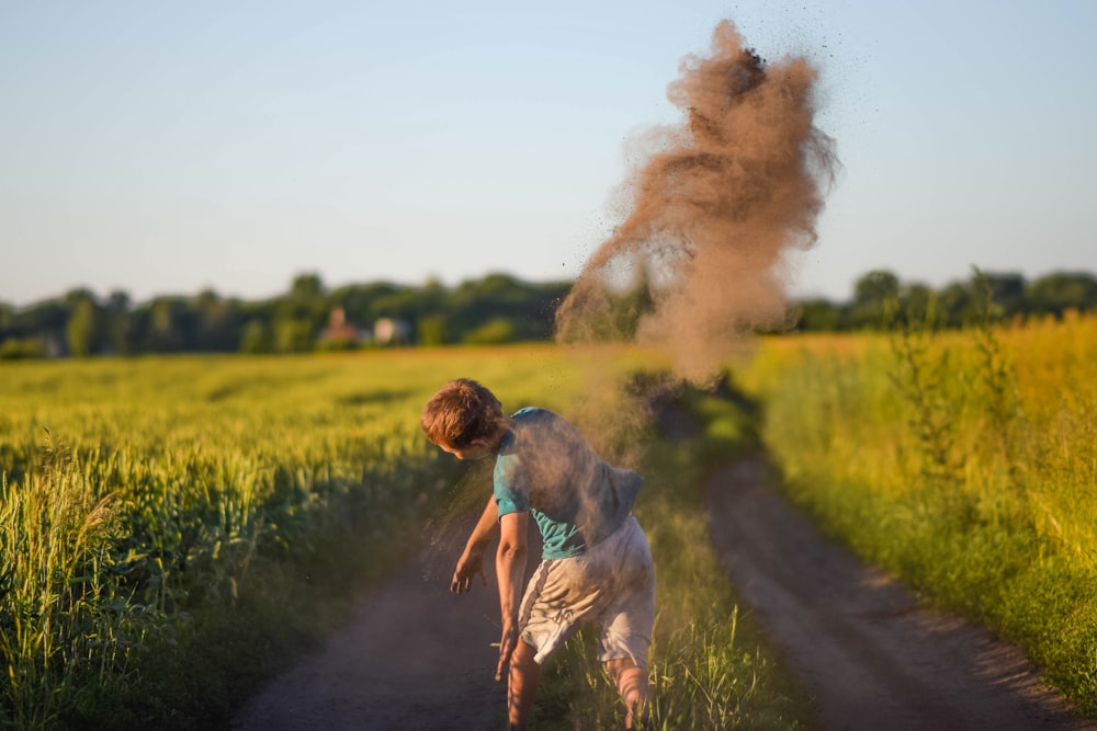 a young boy is walking down a dirt road