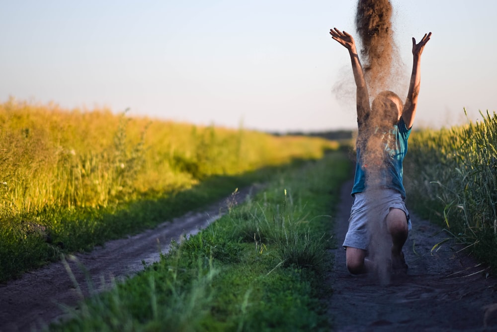 a woman is walking down a dirt road