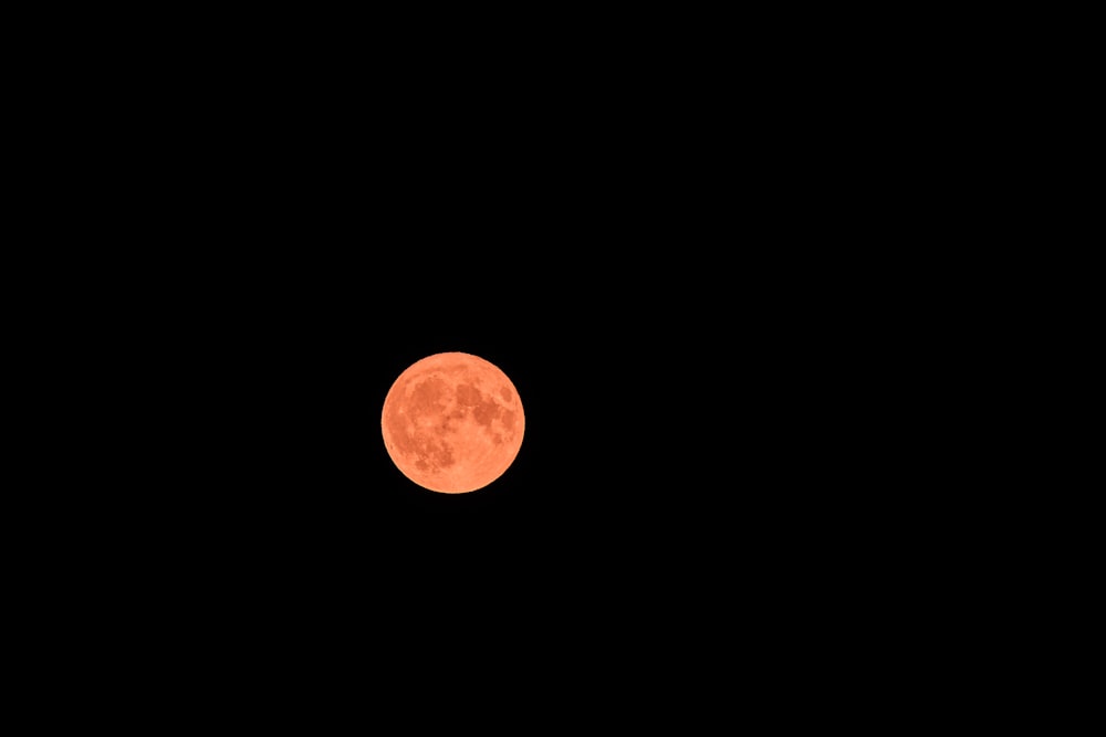 a full moon is seen in the dark sky