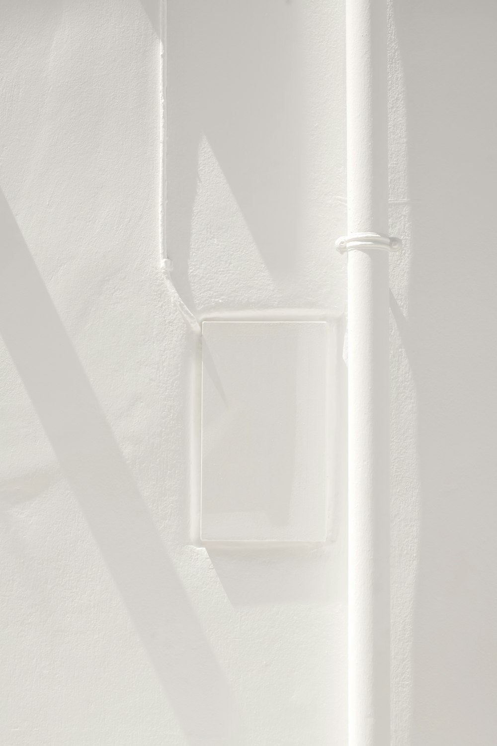 una parete bianca con un interruttore della luce quadrato su di esso