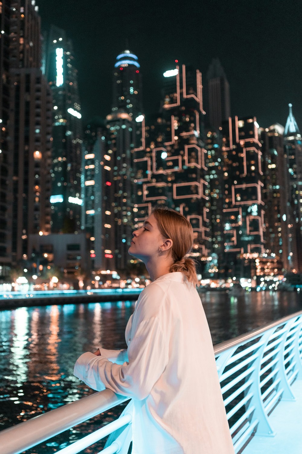 a woman standing on a bridge in front of a city