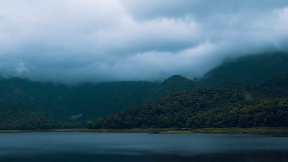 a body of water surrounded by mountains under a cloudy sky