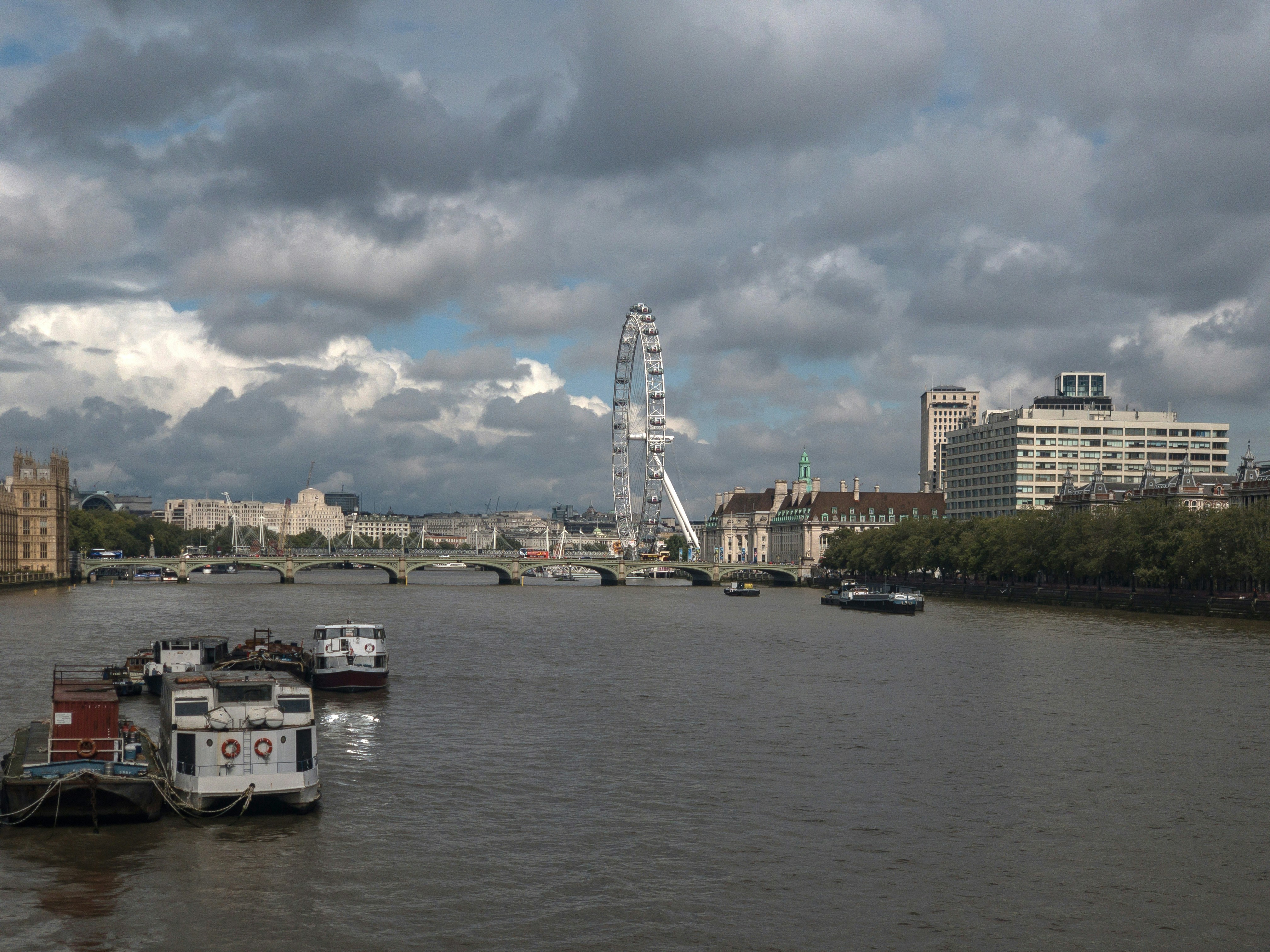 a river filled with lots of boats under a cloudy sky
