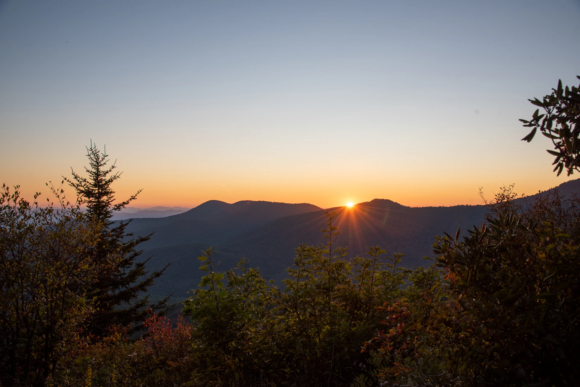 the sun is setting over a mountain range