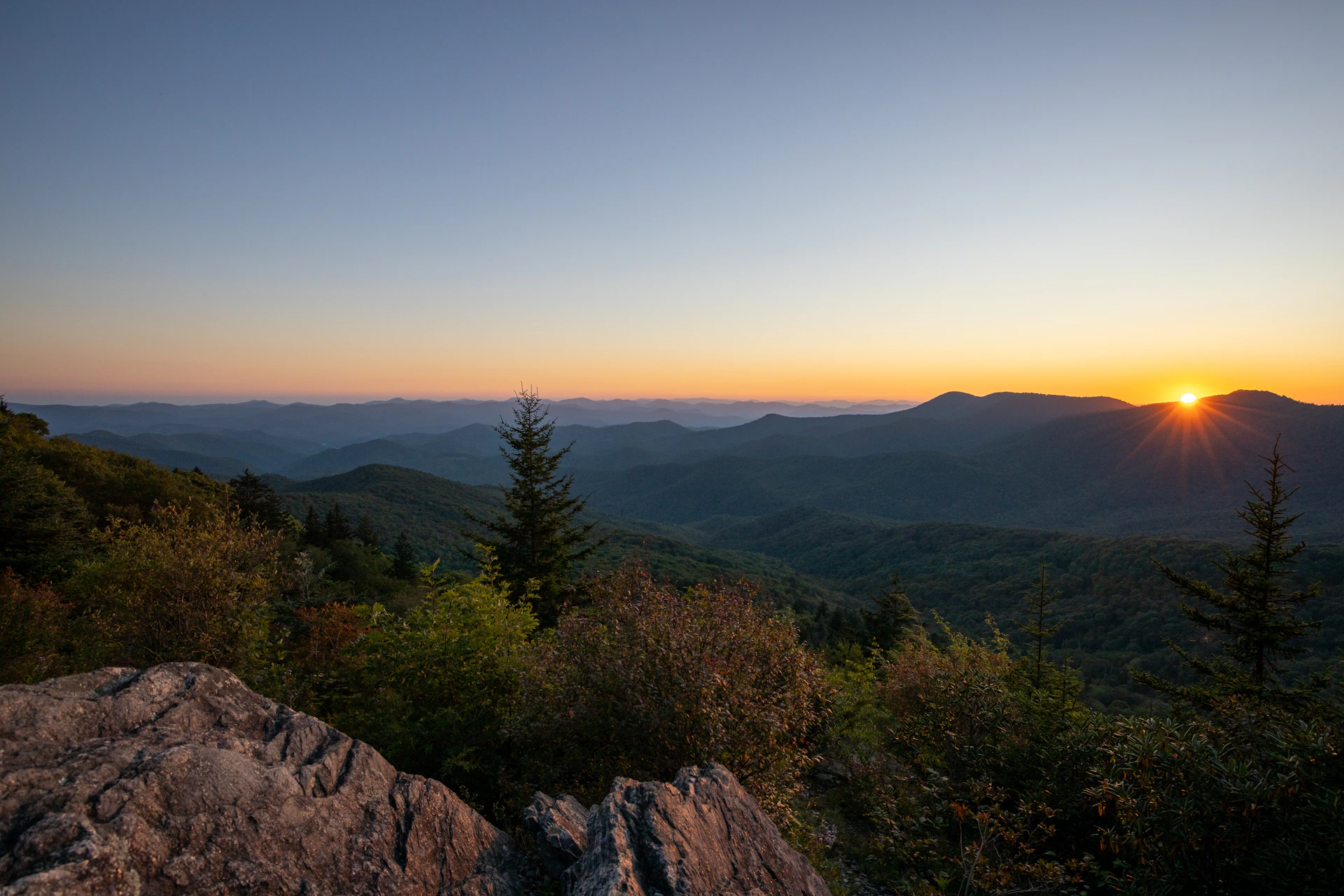 the sun is setting over the mountains in the distance