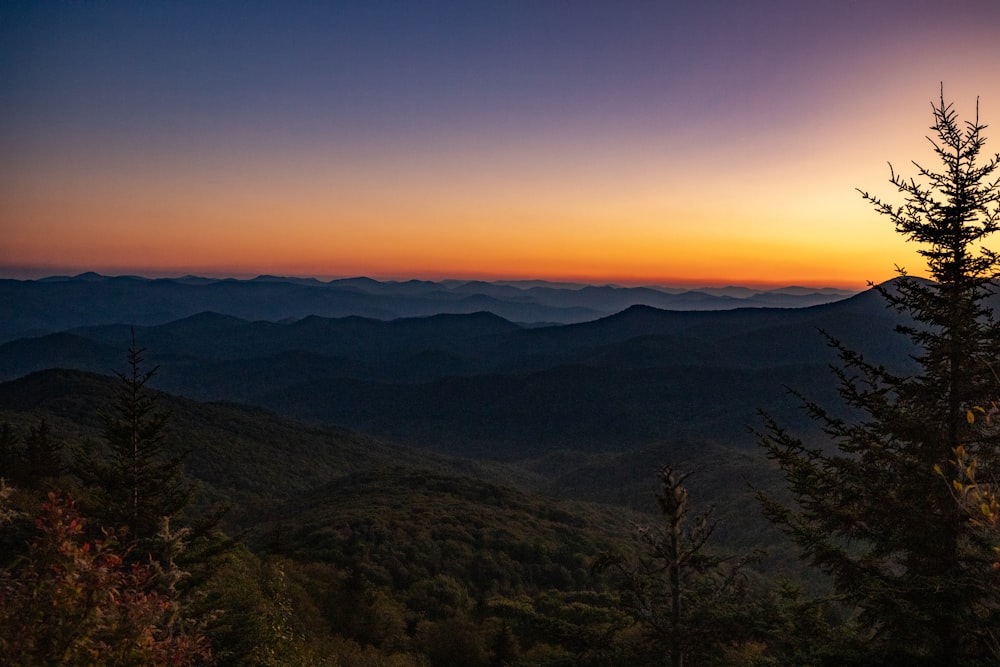 the sun is setting over the mountains in the distance