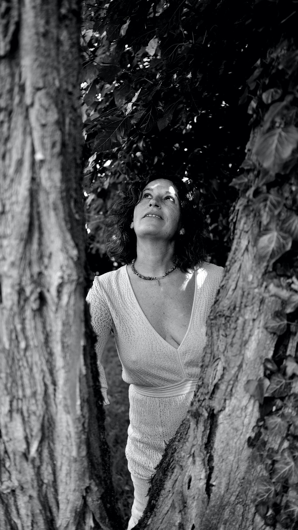 a woman leaning against a tree in a black and white photo