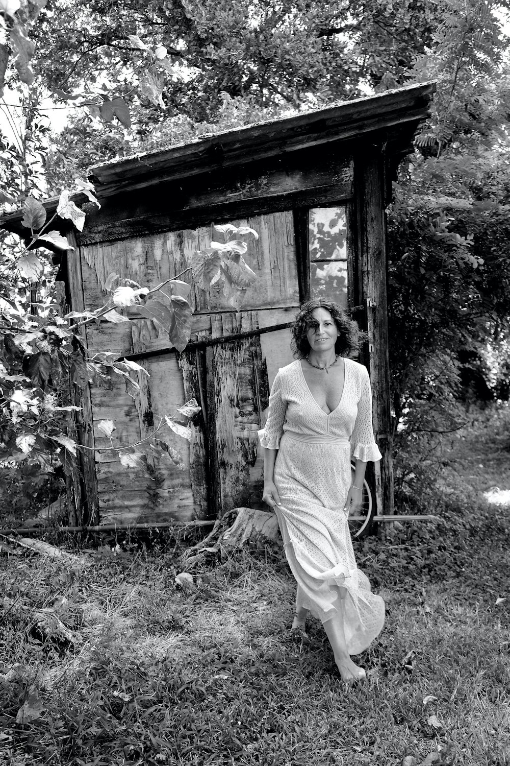 a woman in a long dress walking past a shack