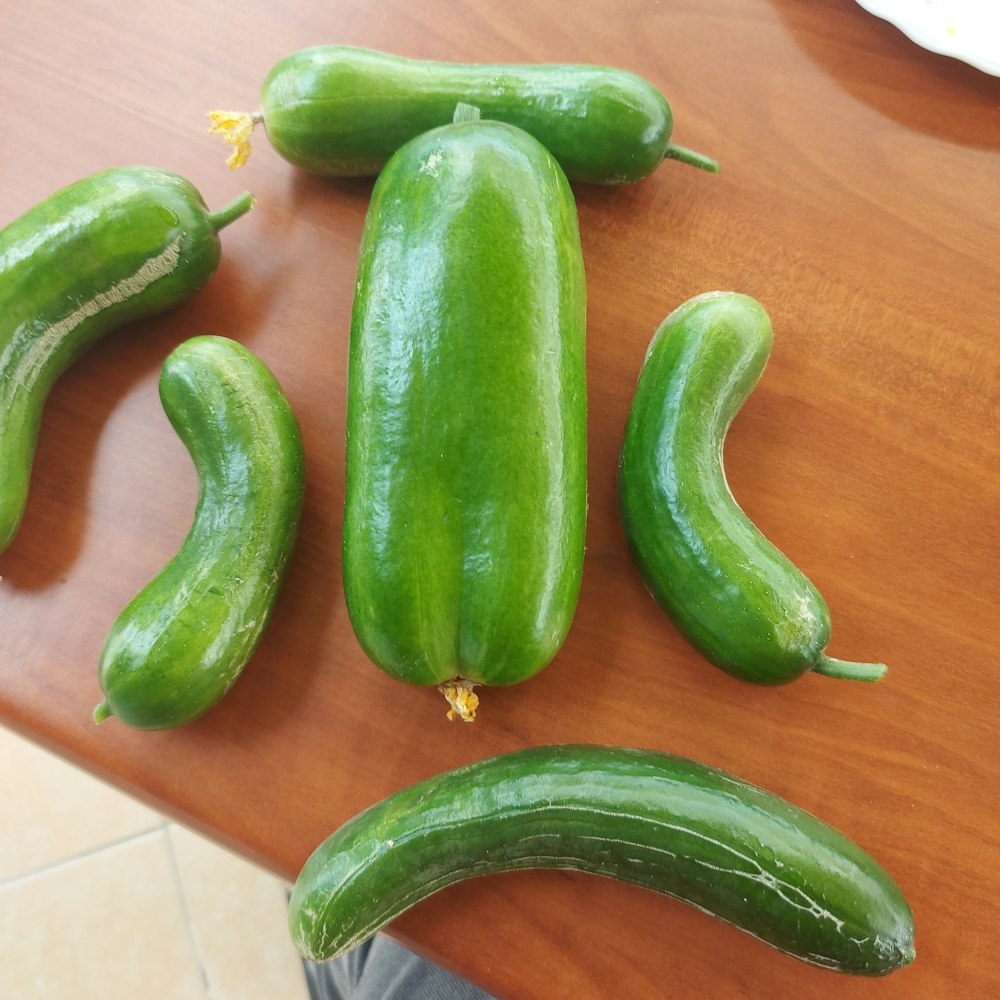 a group of green cucumbers sitting on top of a wooden table