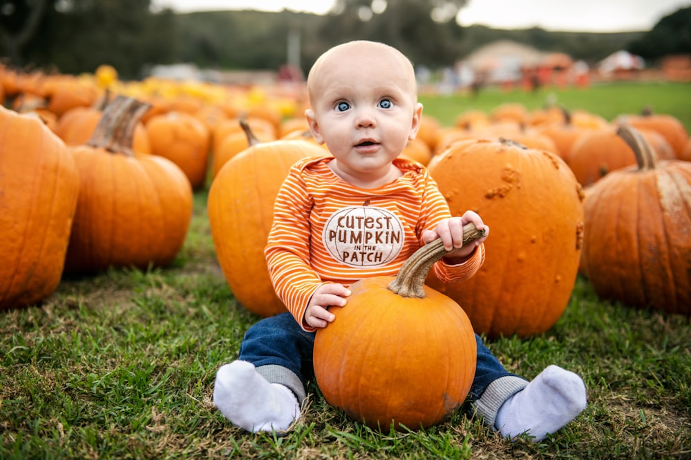 a baby sitting in a field of pumpkins