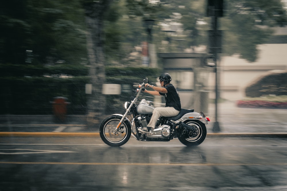 a man riding a motorcycle down a rain soaked street