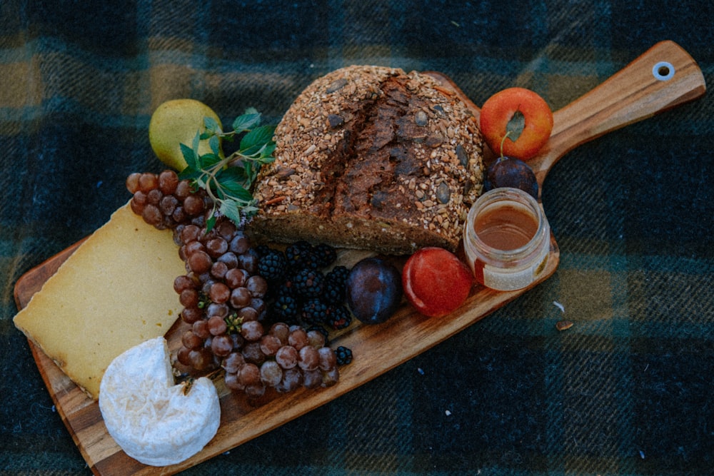 a platter of bread, cheese, fruit, and crackers