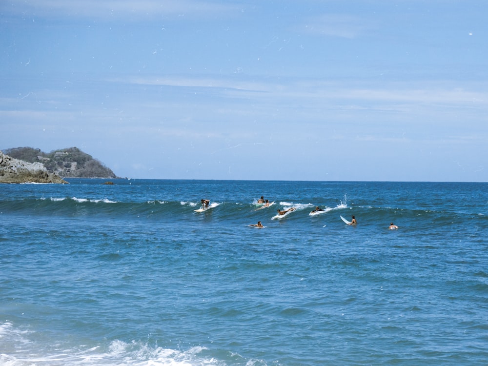 a group of people riding surfboards on top of a wave