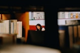 A student studying intently in a bright library filled with books and natural light.