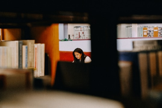 A student studying at a desk surrounded by books and notes.