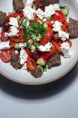 A vibrant Mediterranean salad with fresh tomatoes, cucumbers, olives, and feta cheese on a rustic wooden table