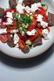 A vibrant Mediterranean salad with fresh tomatoes, cucumbers, olives, and feta cheese in a rustic bowl.