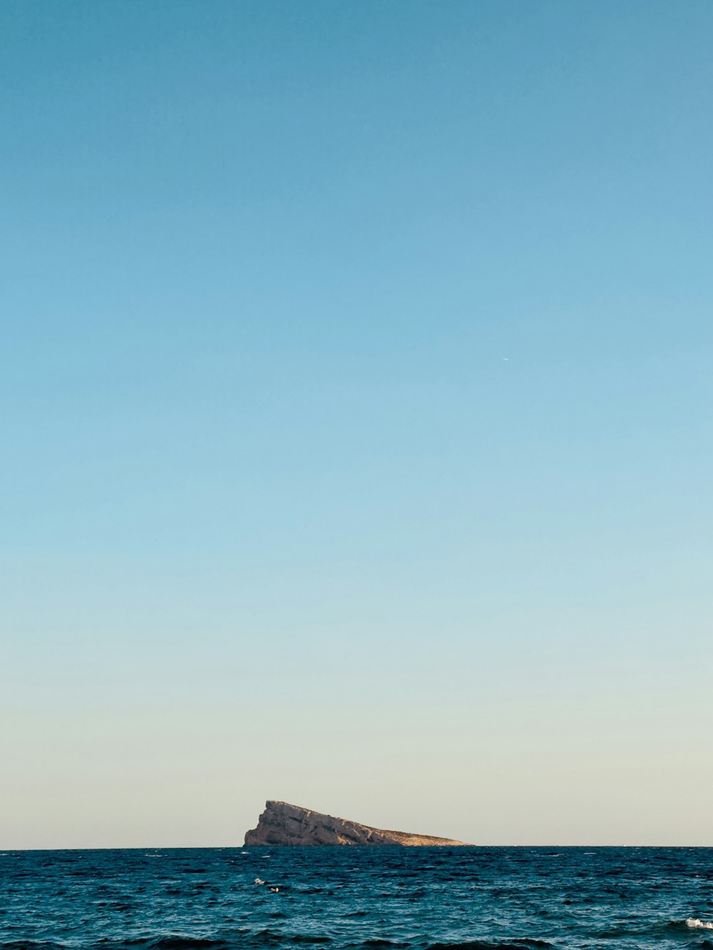 a sailboat sailing in the ocean near a small island