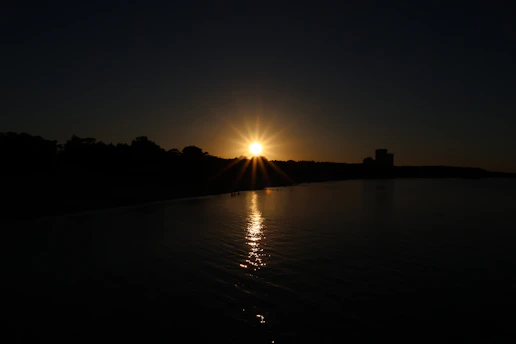 A serene sunset view over the Taj Mahal with warm golden hues reflecting on the Yamuna River.