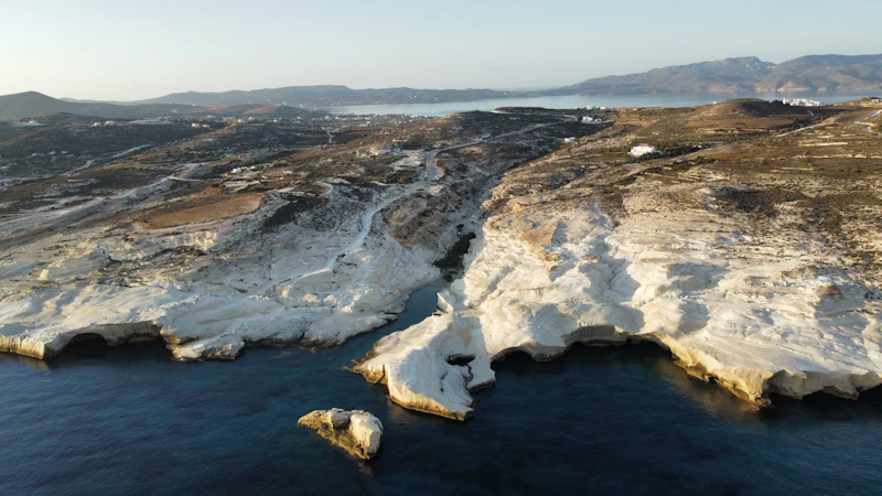 Aerial view of the white rock shelves of Sarakiniko meeting dark water