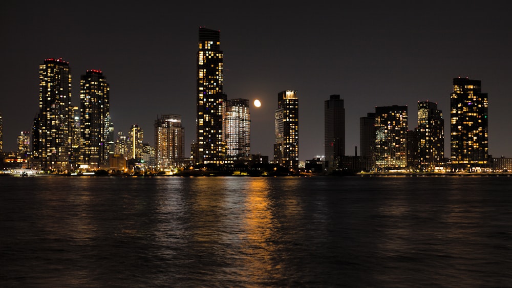 a city skyline at night with a full moon in the sky