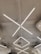 Geometric LED light fixtures are mounted on a white industrial-style ceiling, with an air conditioning unit visible near the center. The lights form intersecting diagonal lines, creating a modern and minimalistic design.