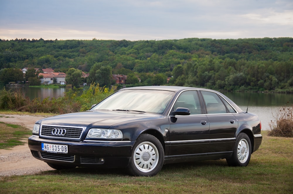 a black car parked in front of a lake