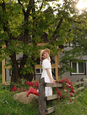 A joyful woman wearing modest evangelical clothing, standing in a sunlit garden.