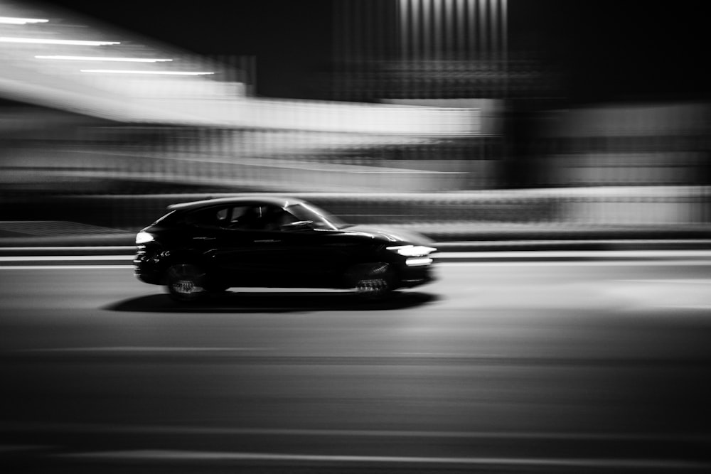 a black car driving down a street at night