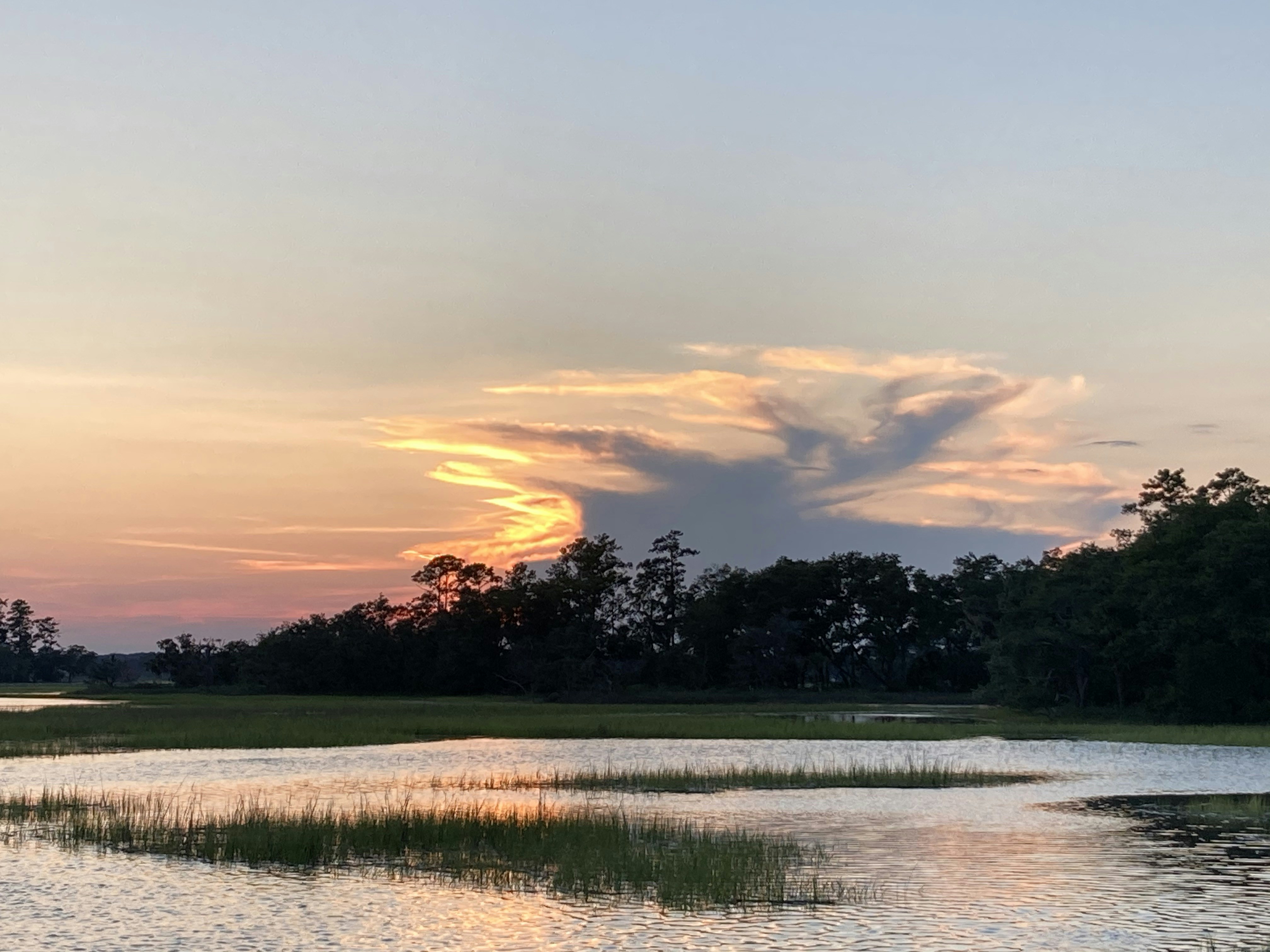 the sun is setting over a lake with trees in the background