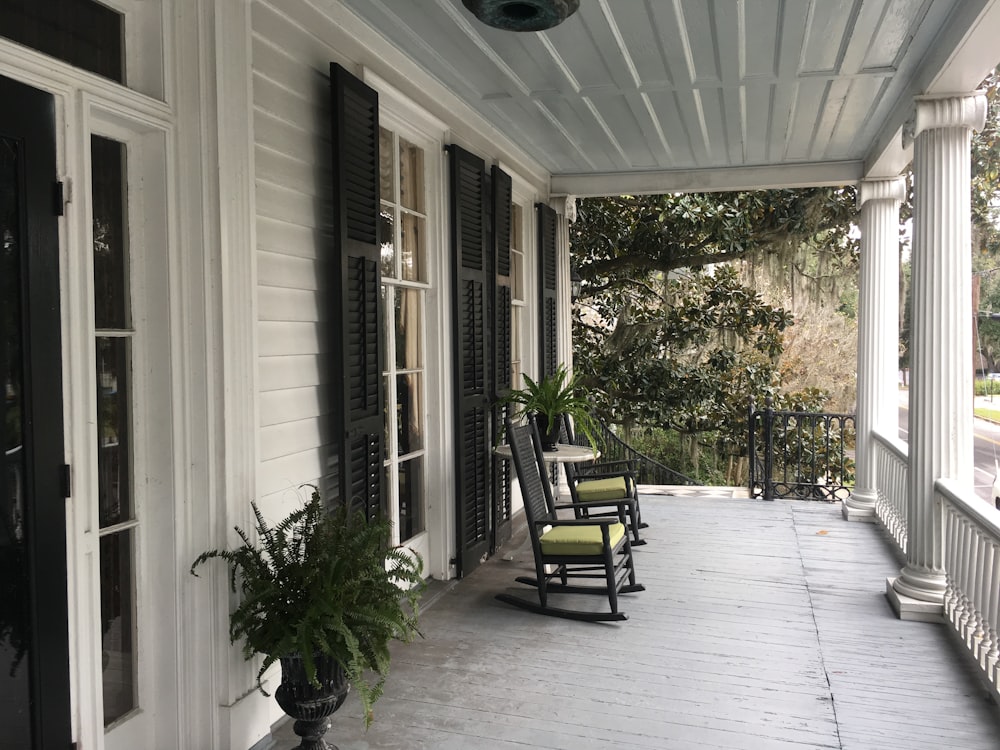 a porch with rocking chairs and a potted plant