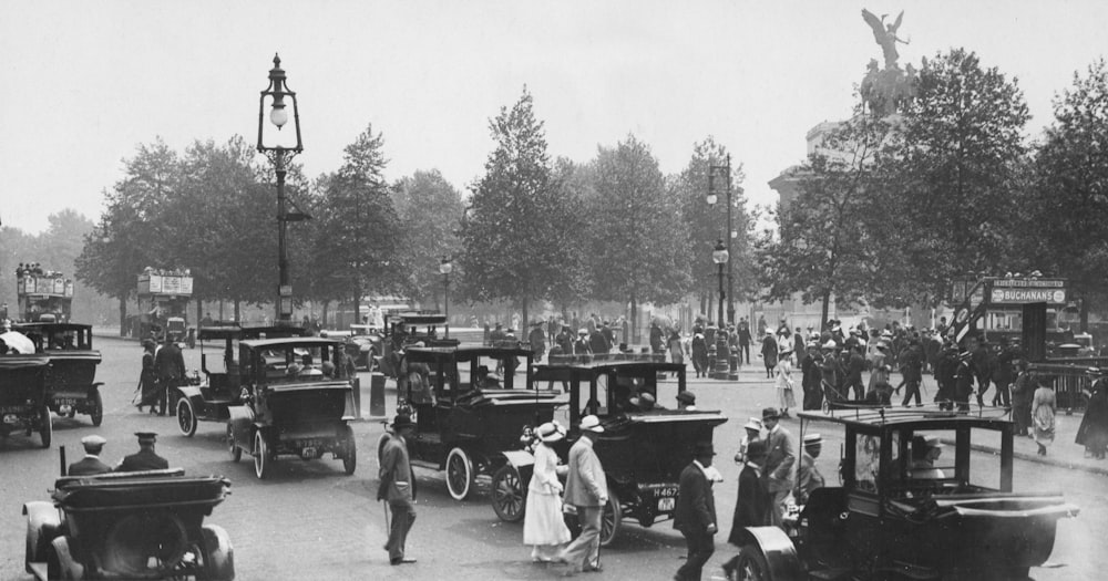 a crowd of people walking down a street next to old cars