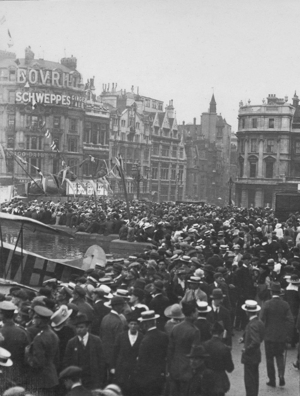 a crowd of people walking down a street next to tall buildings