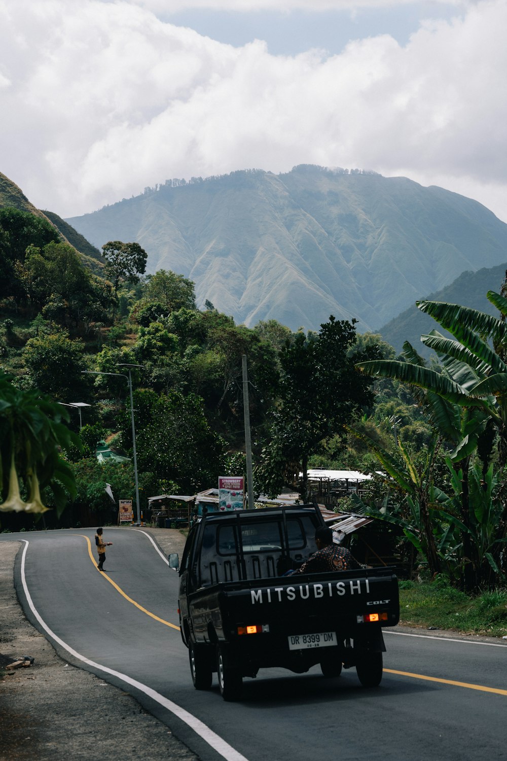 a truck driving down a road with a mountain in the background