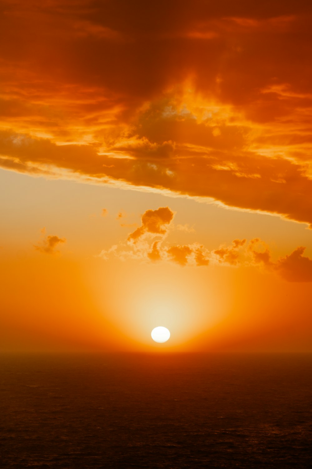 the sun is setting over the ocean on a cloudy day