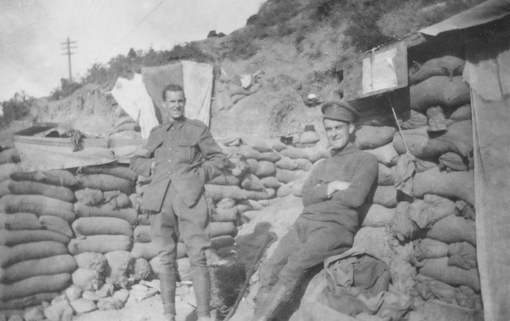 uma foto em preto e branco de um homem de uniforme ao lado de uma pilha de