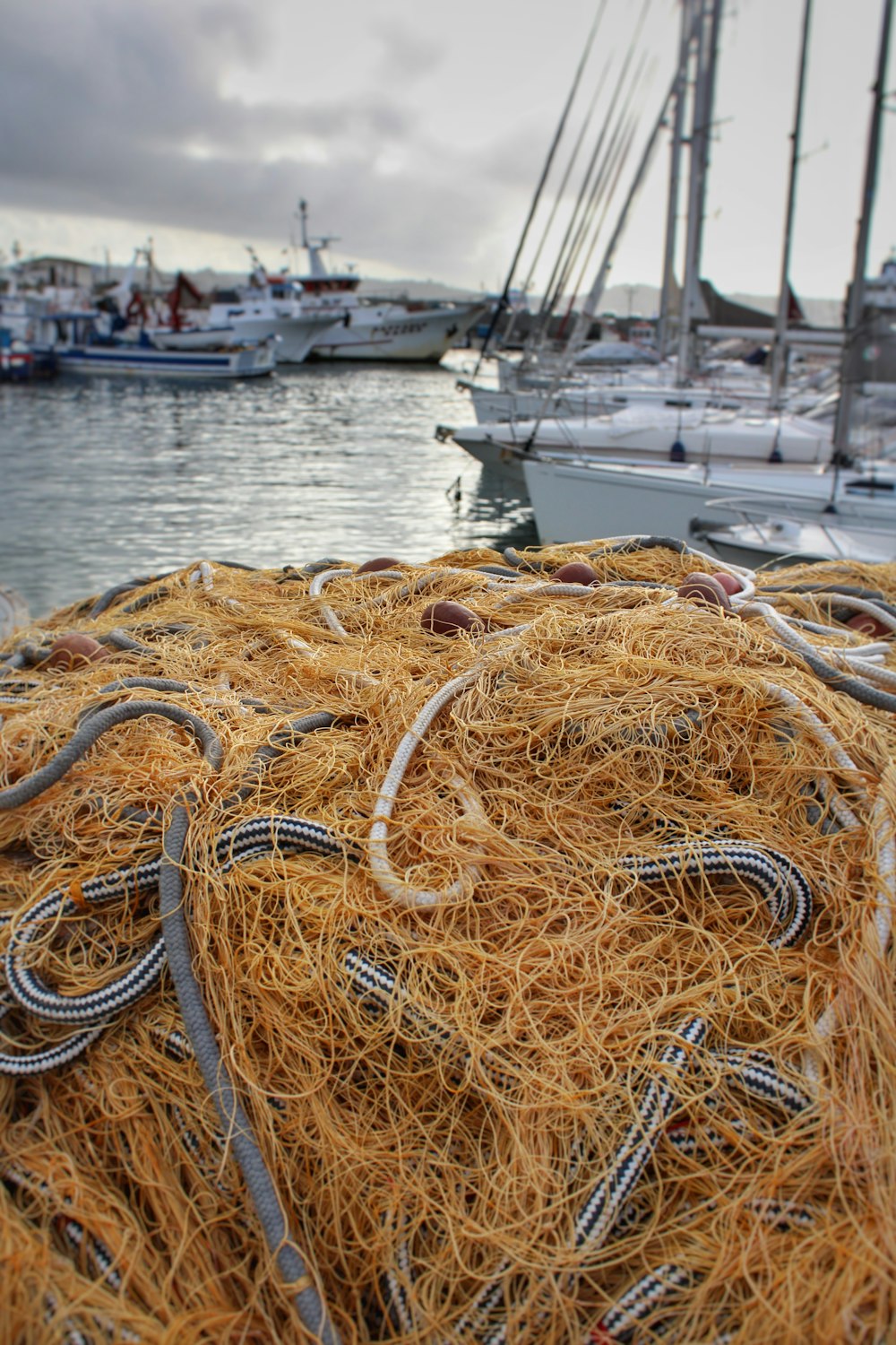a pile of hay sitting next to a harbor filled with boats