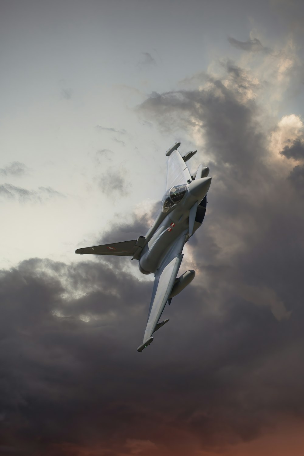 a fighter jet flying through a cloudy sky