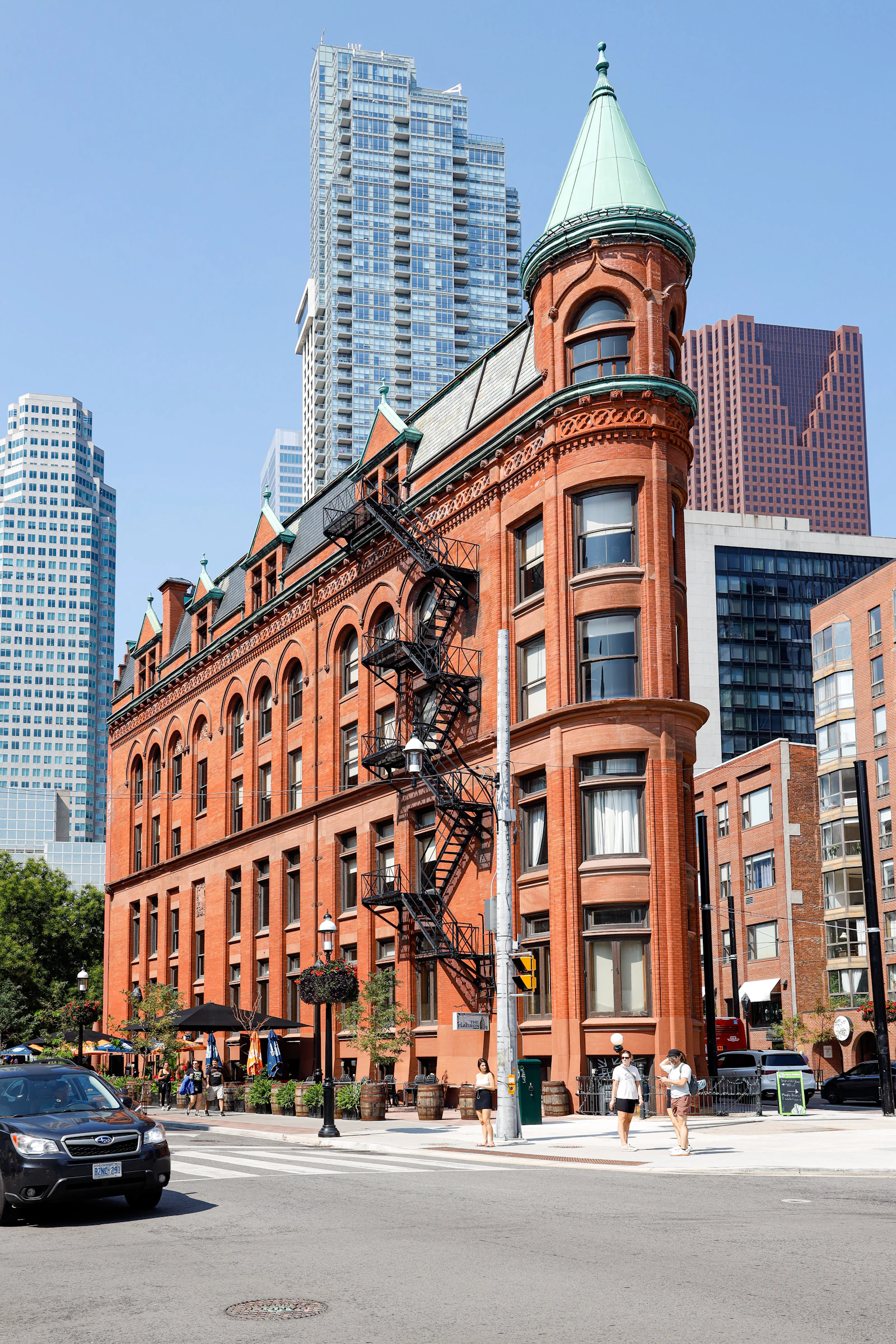 A downtown Toronto street corner with the historic red brick Gooderham Flatiron building and tall office towers behind it