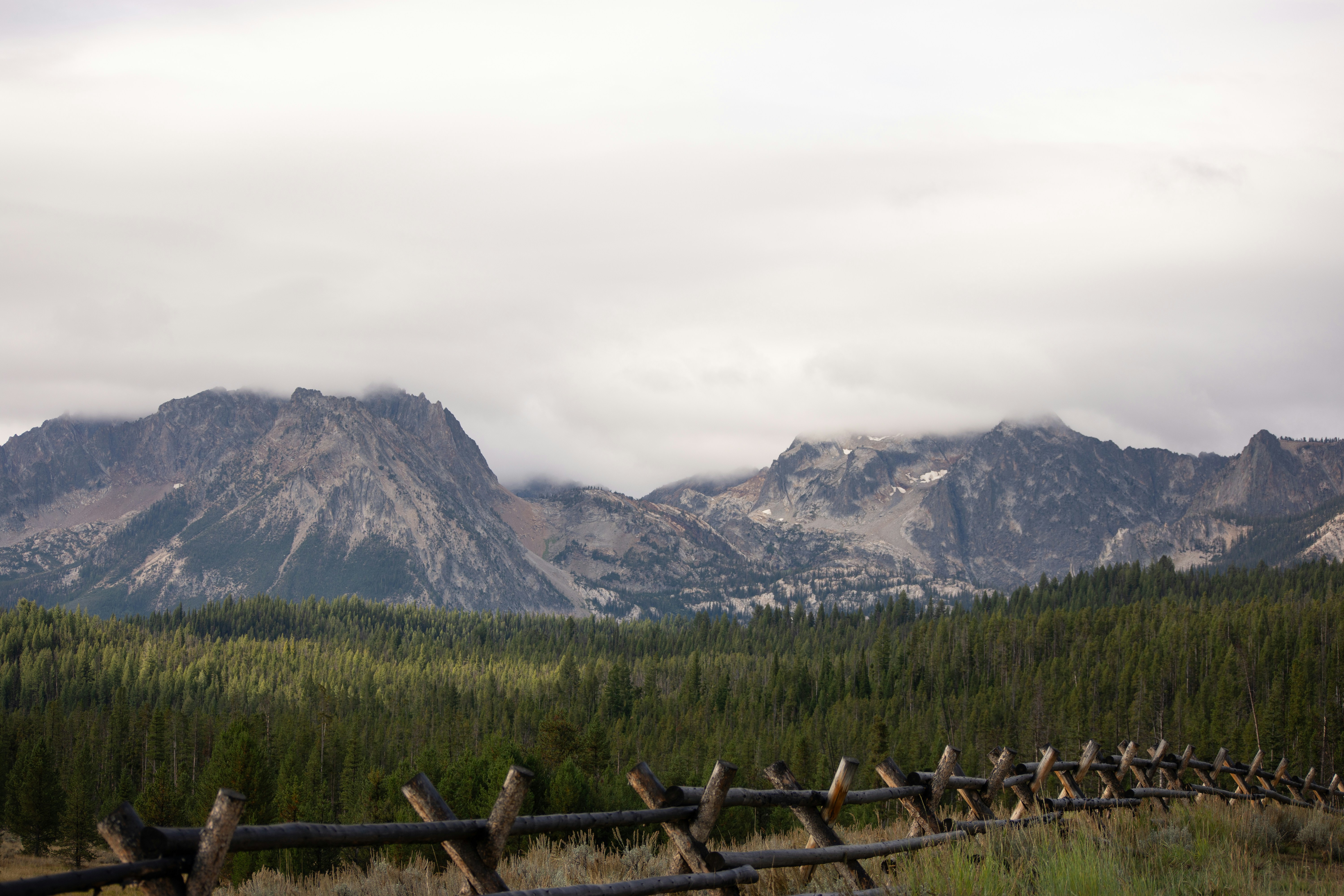 a wooden fence in front of a mountain range, 