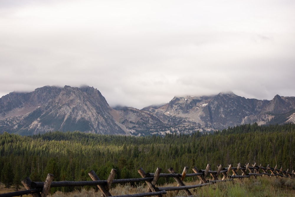 a wooden fence in front of a mountain range