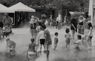 A group of smiling children and families enjoying a sunny community event in a park.