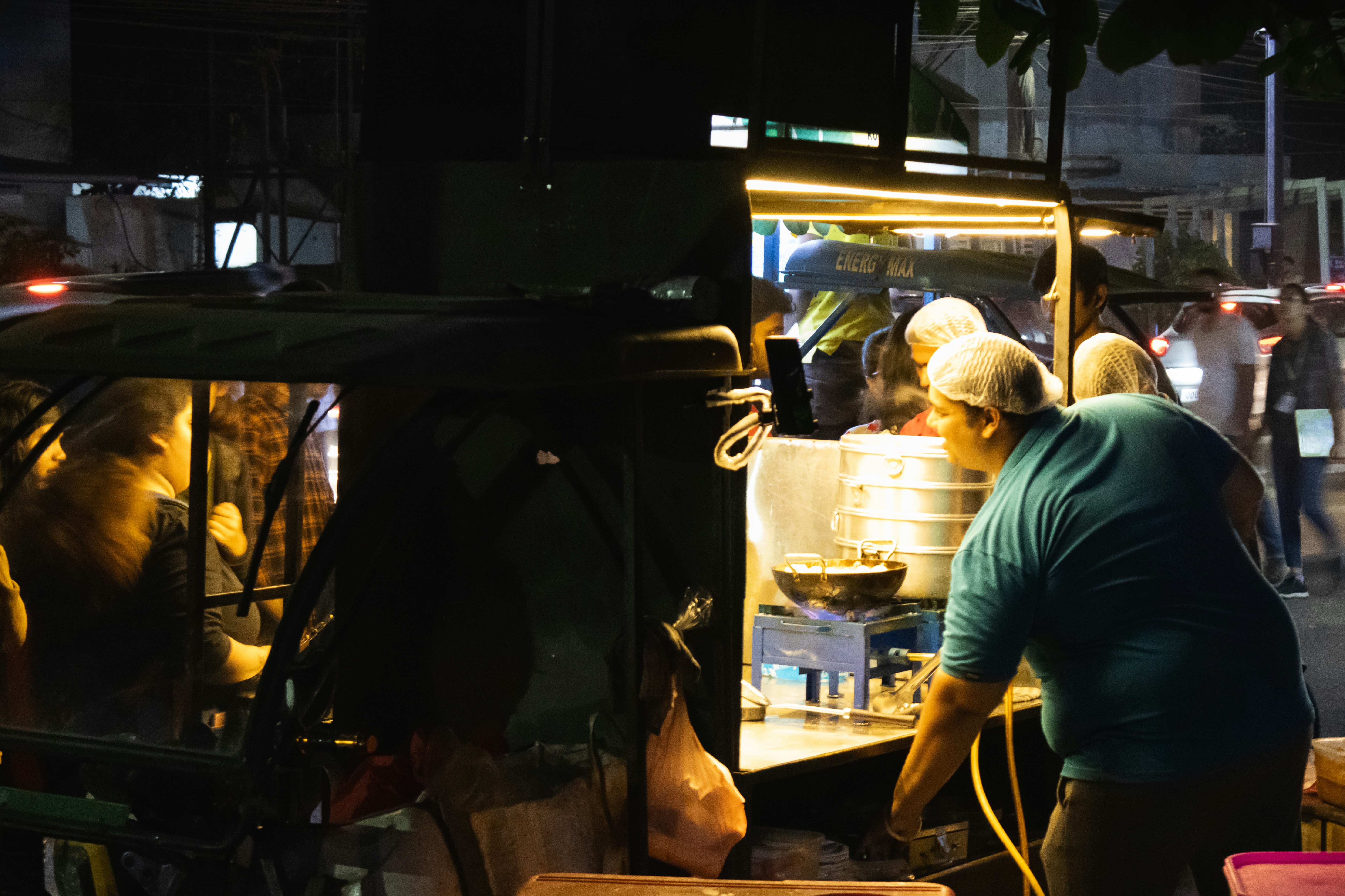 Banaras street food vendor at Godaulia Crossing, evening market scene with glowing stall lights, dark atmospheric street, warm amber tones