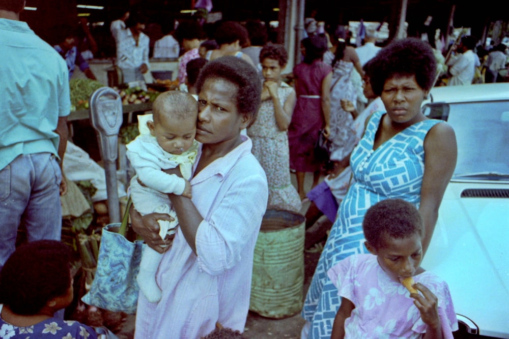 a woman holding a baby in a crowd of people