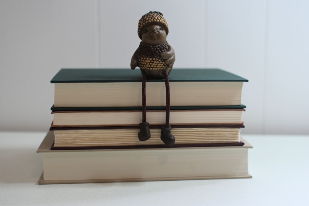 a figurine sitting on top of a stack of books