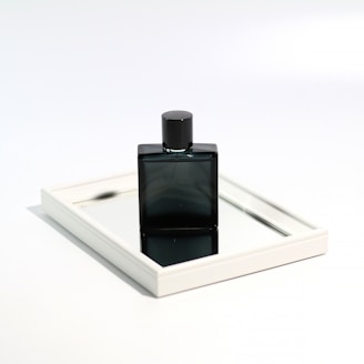 Close-up of a sleek perfume bottle with clean lines resting on a concrete surface, reflecting minimalist architecture.