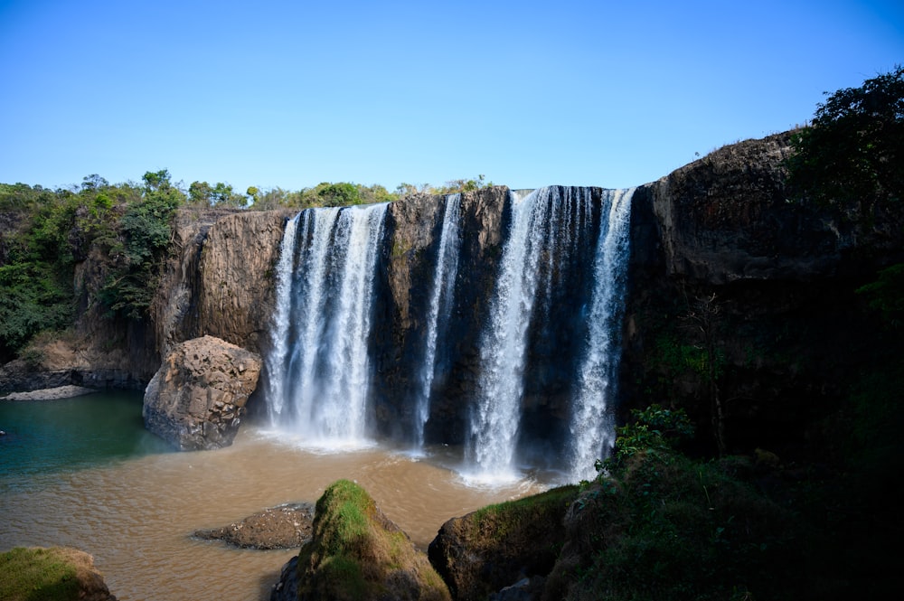 a large waterfall with a body of water in front of it