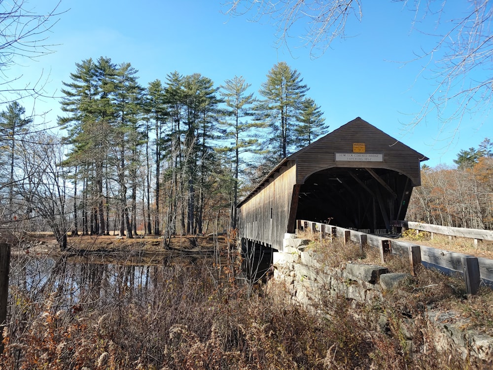 a wooden covered bridge over a river in the woods