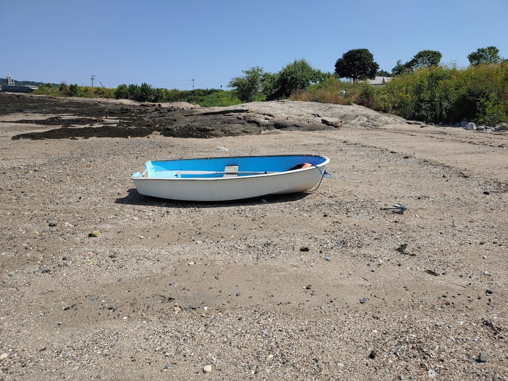 a blue and white boat sitting on top of a sandy beach