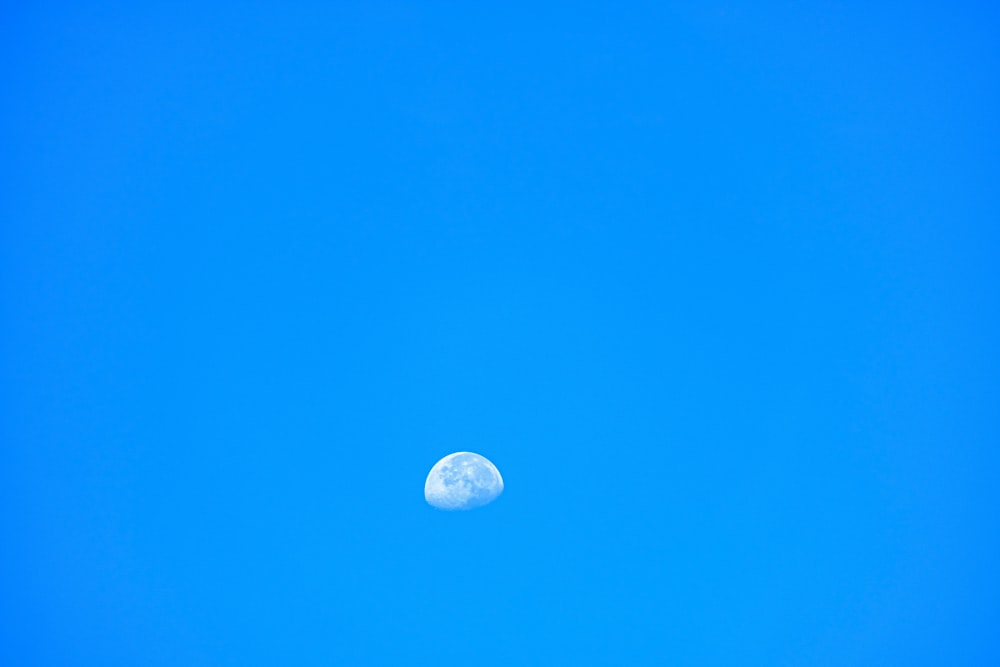 a clear blue sky with a half moon